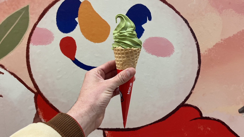 Hand holding a matcha soft serve in a cone from Mixue