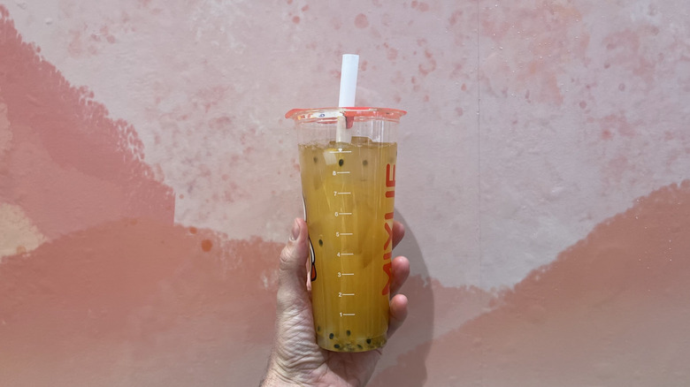 Hand holding a passion fruit drink from Mixue