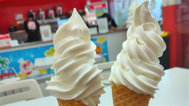 Hand holding a vanilla soft serve in a cone
