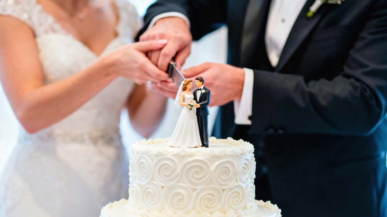 A couple cutting a wedding cake.