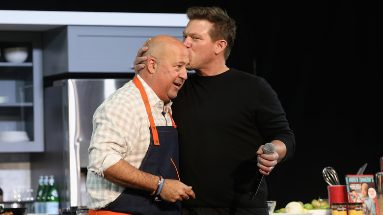 Tyler Florence kisses Andrew Zimmern on the head.
