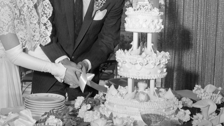 Black and white photo of couple cutting tiered wedding cake