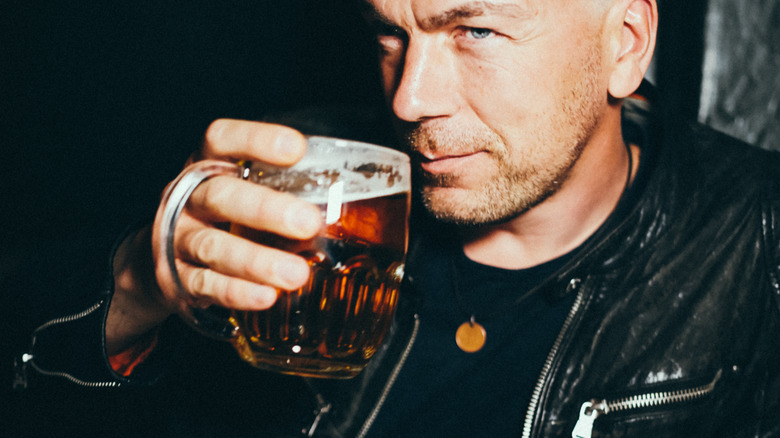 A man brings a mug of beer to his mouth