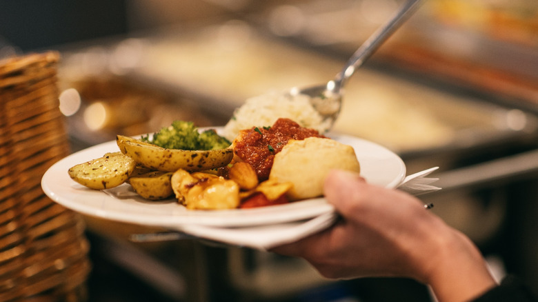 A plate being loaded up at a buffet restaurant