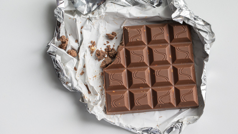A milk chocolate bar partially wrapped in foil