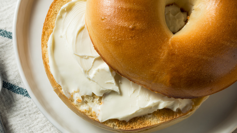 A bagel with cream cheese on it on a plate.
