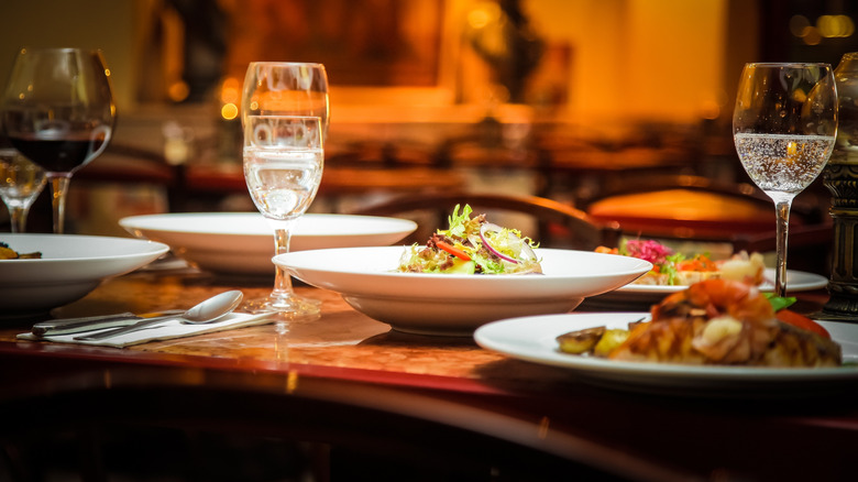 A table at a restaurant with wine glasses and entrees on it
