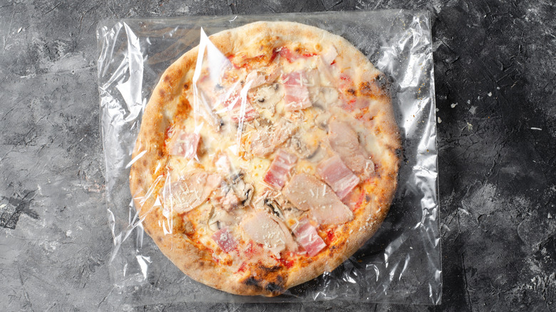 Uncooked frozen pizza in plastic packaging