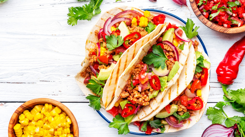 Flour tortilla tacos with ground meat, corn, cilantro, chile peppers