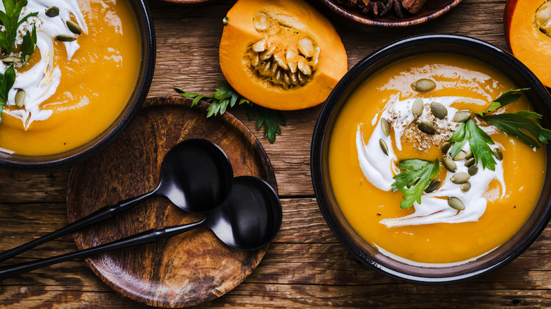 Pumpkin soup in ceramic bowl on wooden rustic table