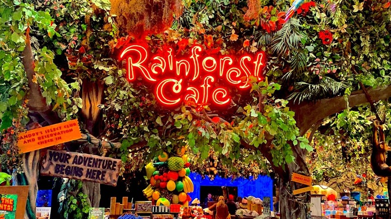 Rainforest Cafe neon sign surrounded by leaves and fake trees