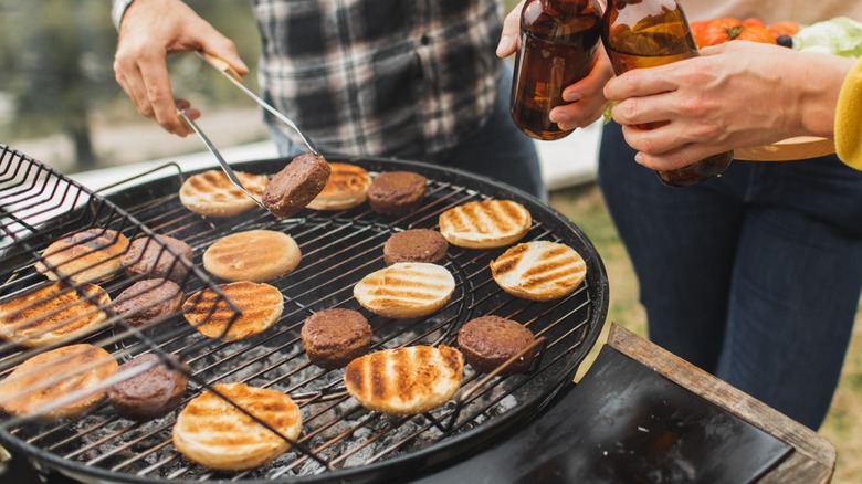 Man grilling burgers with friends.