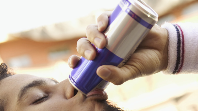 A man drinking a Red Bull.