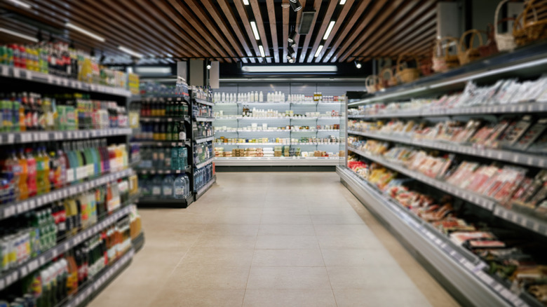 supermarket aisle with bottled sodas, refrigerated section, and dairy section at end