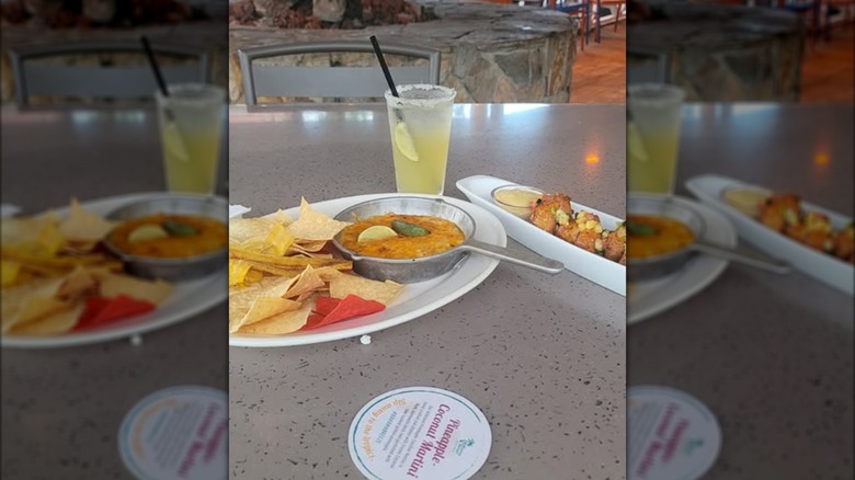 Two appetizer plates and drink sitting on a table inside Bahama Breeze