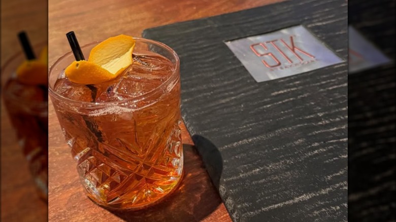 A cocktail placed next to an STK menu