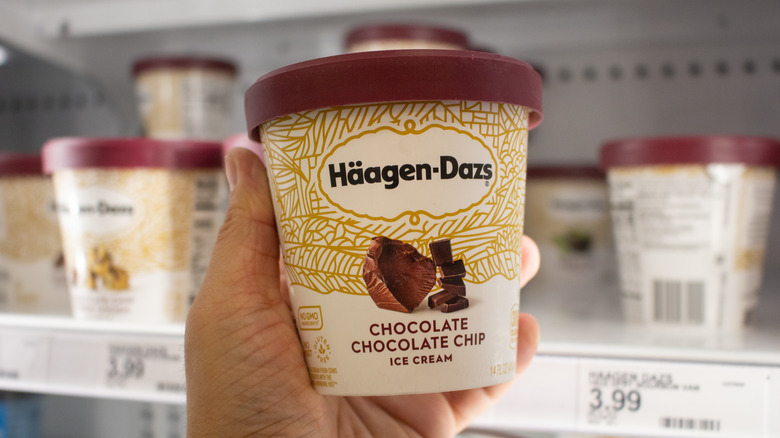 handheld Häagen-Dazs ice cream in front of grocery store freezer