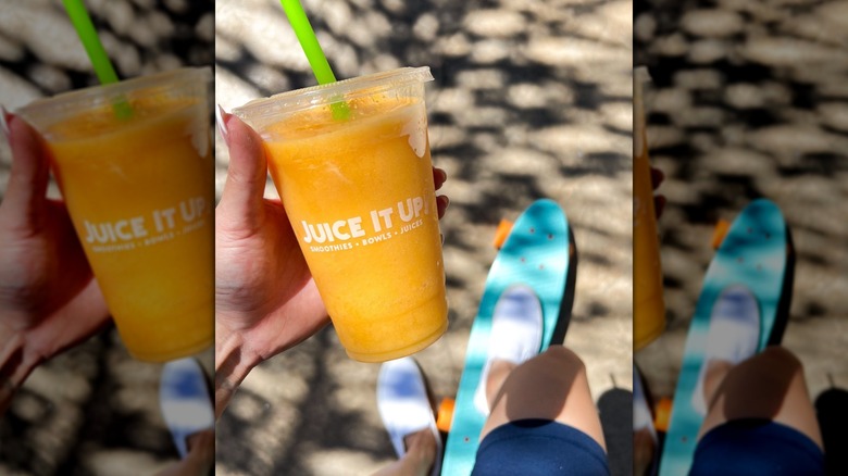 Hand holding Juice It Up cup filled with Passion Fruit-Orange-Guava smoothie