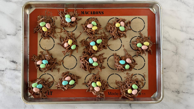 nest-shaped chocolate cookies filled with candy eggs on a baking pan