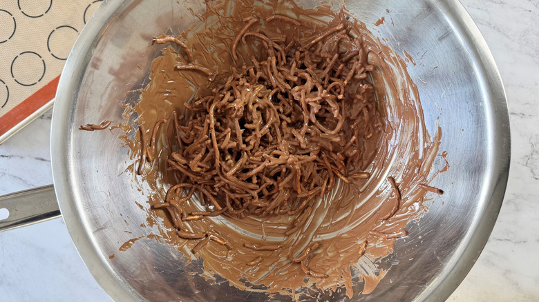 melted chocolate and chow mein noodles in a metal bowl