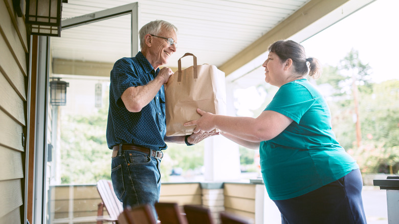 woman handing neighbor a bag