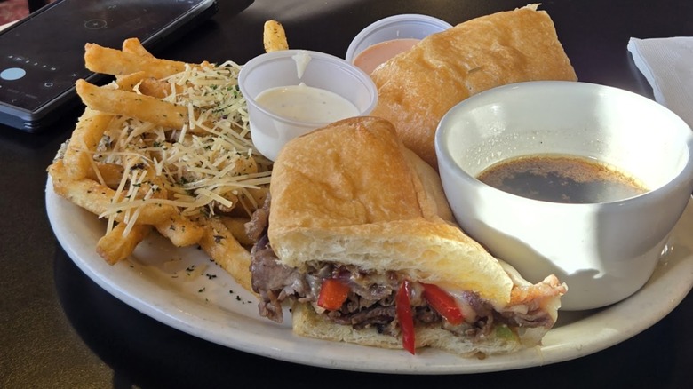 The Prime Rib Dip Sandwich with side of fries and au jus from The Refuge Restaurant & Lounge