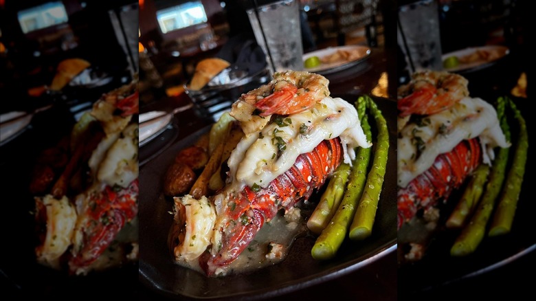 Lobster tail with shrimp and asparagus on a black plate