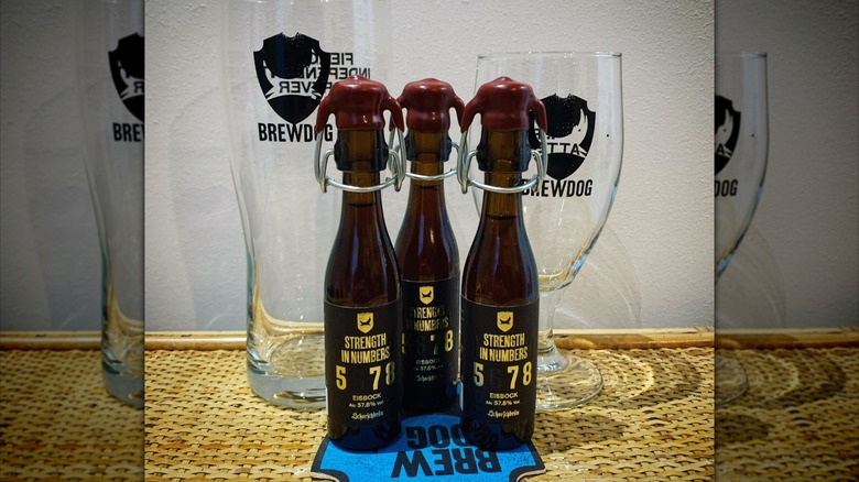 Black and gold label on three bottles of Strength In Numbers beer in front of beer glasses