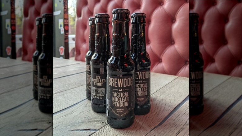 Bottles of BrewDog Tactical Nuclear Penguin beers in dark bottles on table in front of red booth