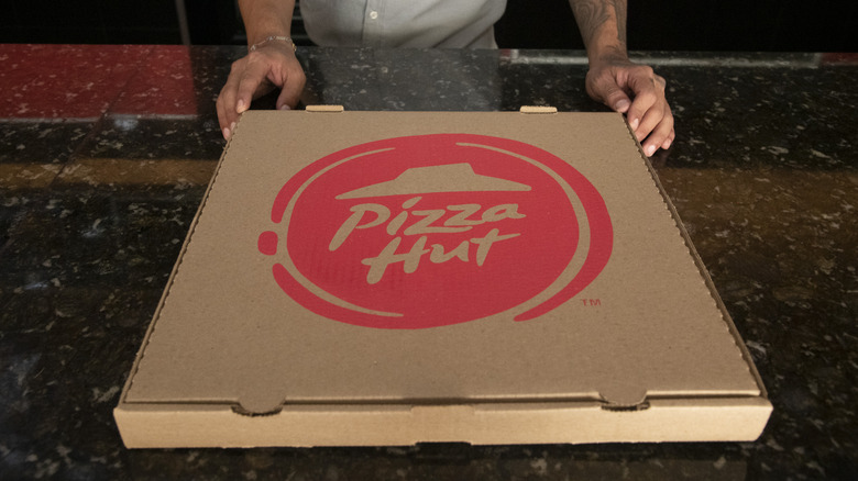 An employee handles a cardboard Pizza Hut box