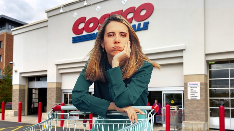 A tired, disgruntled woman with a cart outside a Costco