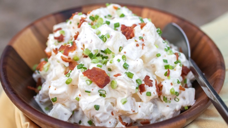 Creamy potato salad with bacon and chives in a wooden bowl