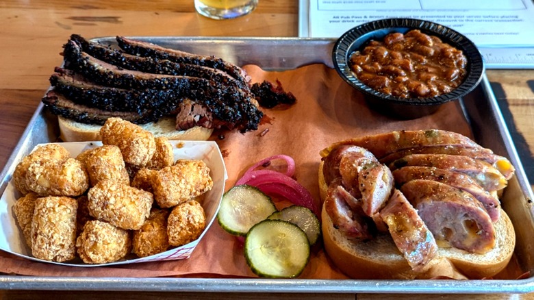 A platter featuring brisket, sausage, tater tots, and beans from 3Halves Brewpub & BBQ