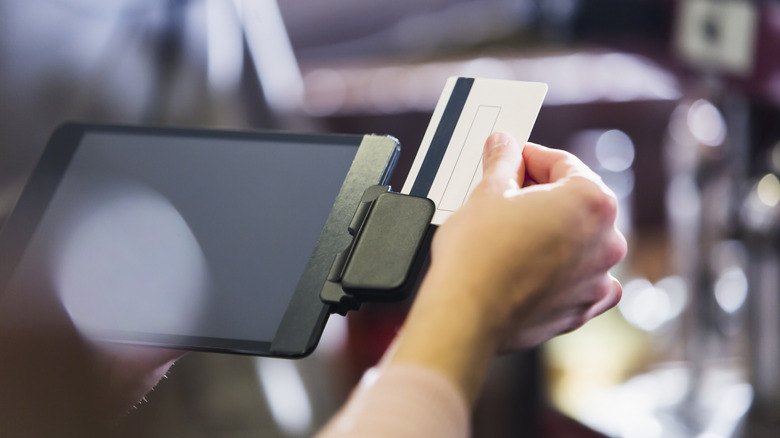 A hand swiping a card at a register.