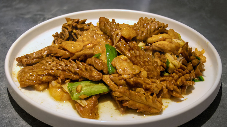 Cooked tripe with green onions on a white plate