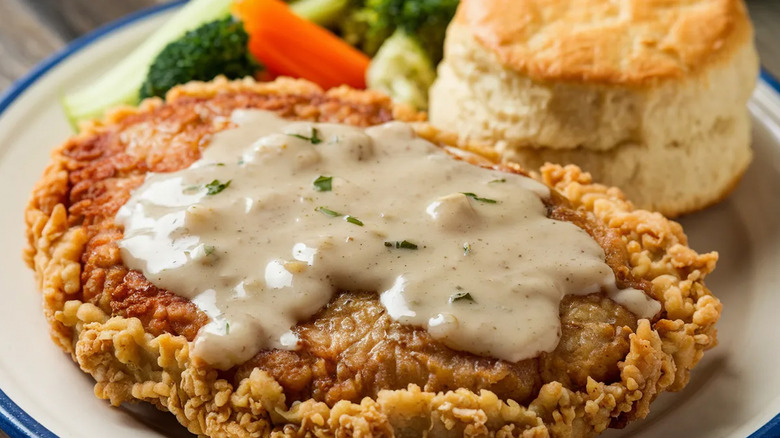 Chicken fried steak on a plate with vegetables and a biscuit at Cracker Barrel
