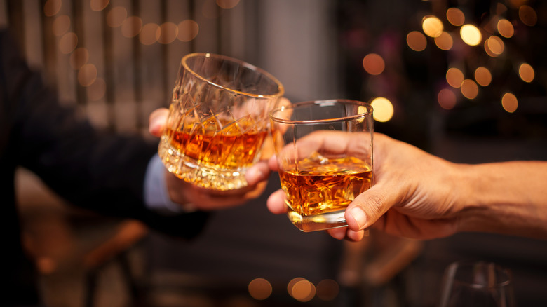 glasses of bourbon held and toasting