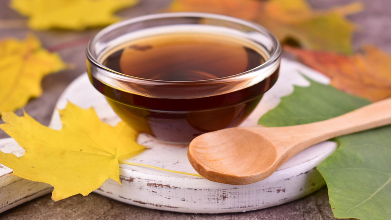 maple syrup in a glass bowl with spoon and maple leafs