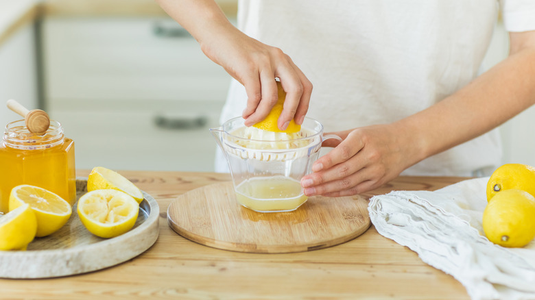 Hands squeezing lemons with hand juicer