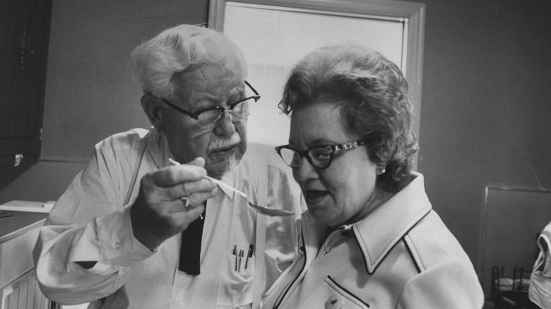 Colonel Sanders giving a woman a taste of food on a spoon