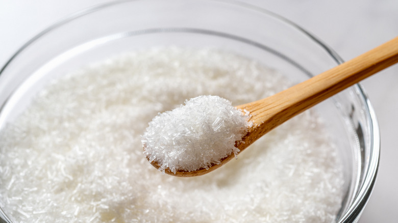 Glass bowl of MSG with some on a wooden spoon