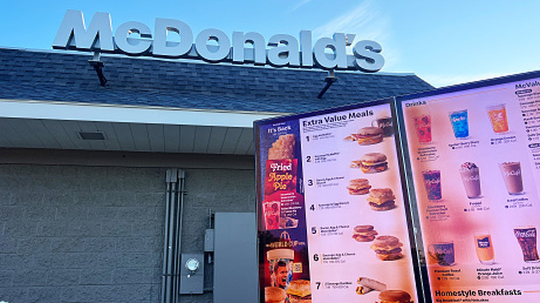 A McDonald's sign on top of a restaurant, next to a digital menu board showing Extra Value Meals.