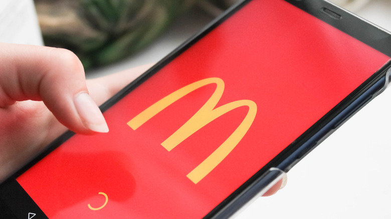 A smartphone showing a red McDonald's app on the screen.