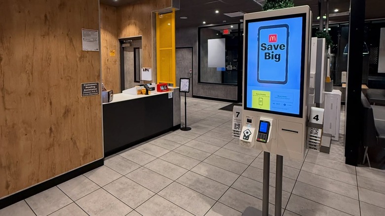 A McDonald's pay kiosk in the middle of an empty McDonald's restaurant.
