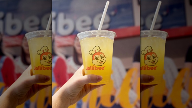 Hand holding cup of pineapple quencher from Jollibee