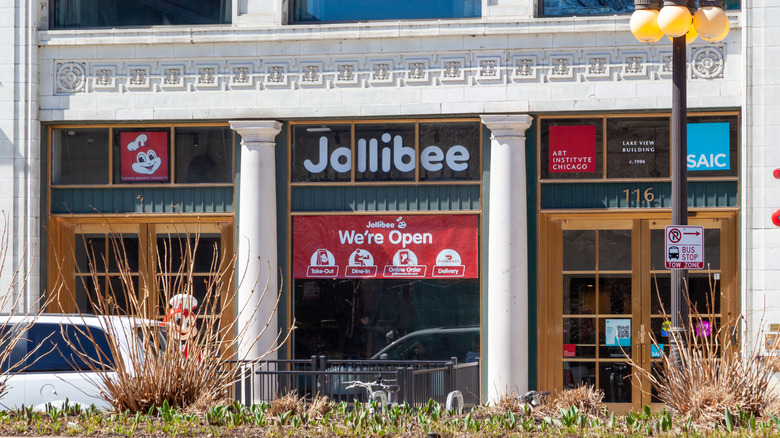 A store front of Jollibee with a "we're open" banner across the front.