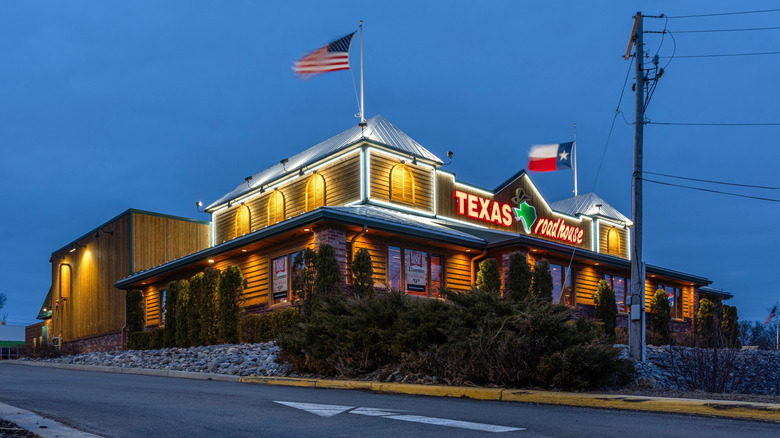 The outside of a Texas Roadhouse restaurant illuminated at night