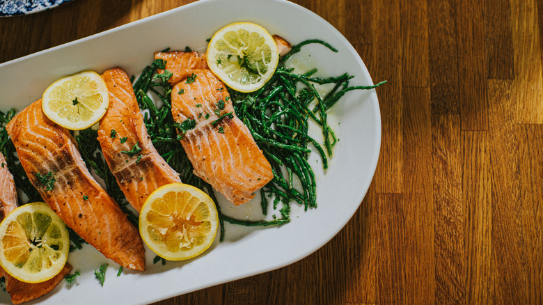 Cooked salmon fillets on a white platter with lemon slices