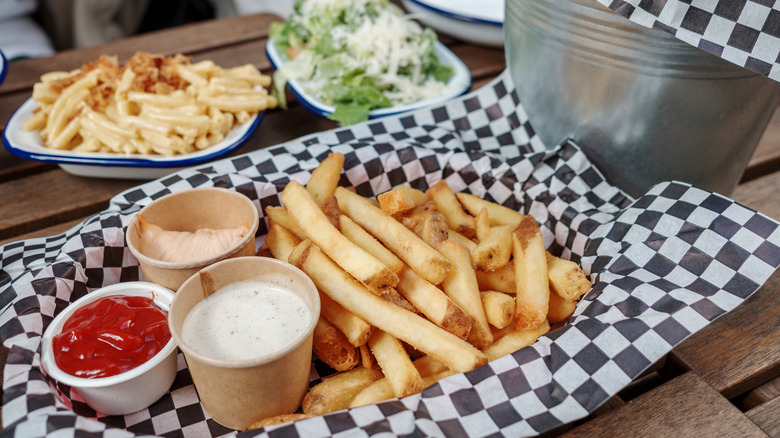 French fries on checkered paper with cups of ketchup and ranch