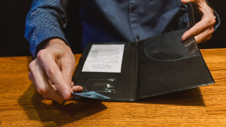 Hands placing a credit card into a restaurant check holder